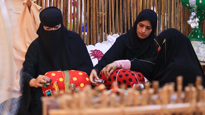 Des femmes émiratie tissent du fil selon la méthode Al Talli, une technique de tissage locale traditionnelle, lors d'un festival annuel du patrimoine à Al-Ain le 10 novembre 2023. (KARIM SAHIB / AFP)