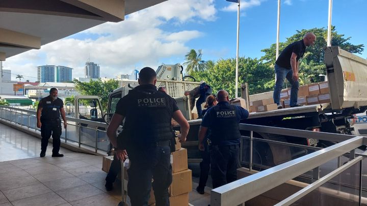 Des policiers municipaux et des agents de la mairie déchargent le matériel de vote récupéré à l'aérodrome, le 2 juin 2024, à Nouméa (Nouvelle-Calédonie). (SANDRINE ETOA-ANDEGUE / RADIOFRANCE)